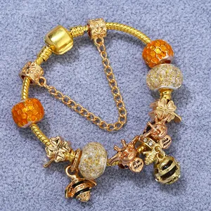 Golden snake chain bracelet with honeybee and honey pot charms on purple background