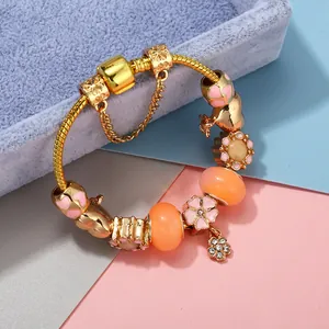 Golden charm bracelet with pink enamel hearts and crystal flower pendant on jewelry stand