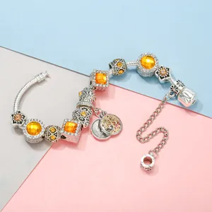 Silbernes Perlenarmband mit gelben Kristallen und Blumenanhängern auf buntem Grund