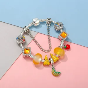 DIY charm bracelet with fruit-themed beads, yellow crystals and red cherry pendants
