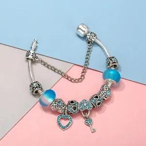 Pulsera con dijes de corazón y llave en cristal azul con cadena de serpiente plateada