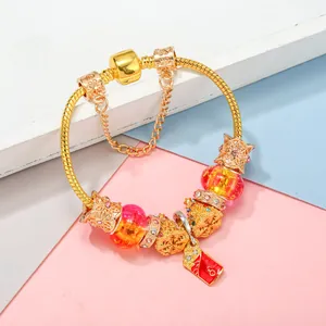 Golden snake chain bracelet with Ferris wheel beads, orange glass, and red enamel charms