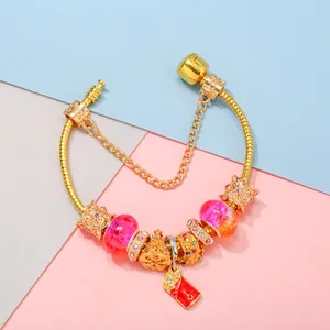 DIY charm bracelet with gold snake chain, pink glass beads, and festive tree pendant