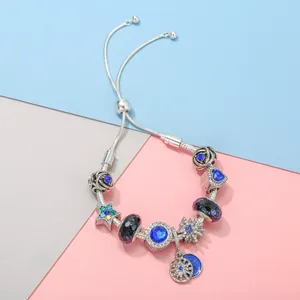 Silver charm bracelet with blue star and heart pendants on a geometric tricolor background