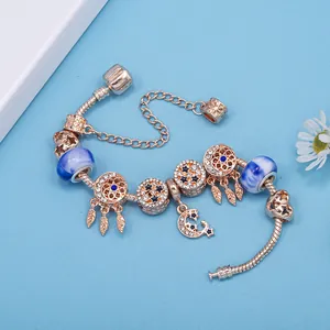 Pulsera de cuentas oro rosa con colgantes de luna y amuletos atrapasueños azules en fondo azul