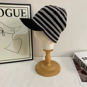 Detailed close-up of knitted black and gray striped beanie with brim on a model head