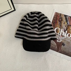 Detail of knitted stripe baseball cap with black brim on a minimalist textured background