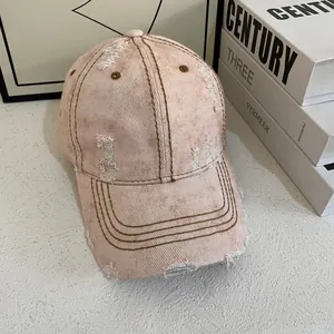 Detailed macro view of the distressed pink canvas baseball cap with stylish frayed holes