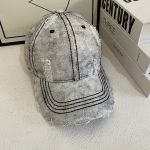 Close-up of distressed grey acid-wash denim baseball cap with stylish ripped hole detail