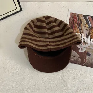 Detail of striped knitted baseball cap showing brown textured fabric and soft inner lining