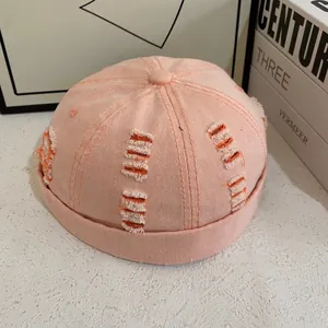 Dettaglio del cappello docker in denim rosa con fori sfrangiati e trama retrò usurata