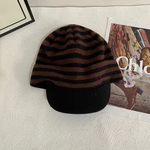 Close-up of brown and black striped knit beanie featuring a solid black brim detail