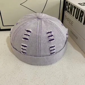 Dettaglio del cappello docker in denim lilla con bordi sfrangiati e cuciture a contrasto
