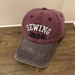 Nahaufnahme der Vintage-Baseballkappe mit roter Krone, grauem Schirm und SEWING-Stickerei