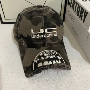 Close-up of distressed camouflage baseball cap with UC Undercontrol embroidery and vintage torn edges