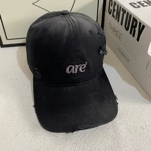 Close-up of a black distressed baseball cap featuring grey 'are²' letter embroidery