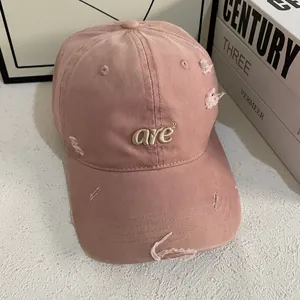 Distressed pink baseball cap with embroidery and ripped details for a street style look