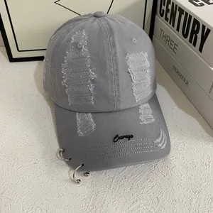 Close-up of gray cotton baseball cap with distressed holes and metal rings decoration