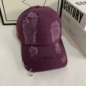 Detail of dark purple cotton baseball cap with ripped effects, metal rings and Courage embroidery