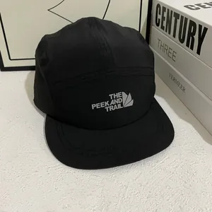 Detalle del logo Peek and Trail en una gorra de camping negra de secado rápido
