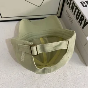 Detail of adjustable metal buckle and distressed cotton fabric on light green baseball cap