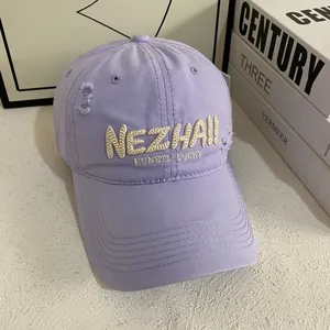 Close-up of distressed lavender baseball cap with embroidered lettering on twill fabric