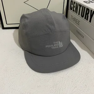 Detalle macro de gorra gris de cinco paneles con textura de rejilla y logotipo