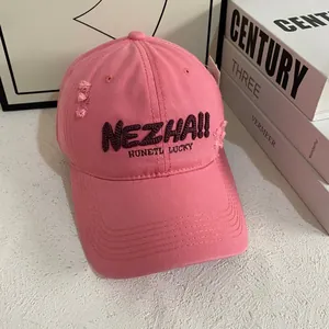 Close-up of pink baseball cap with purple embroidery and distressed ripped details