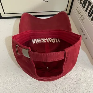 Detail view of dark red baseball cap back with silver metal buckle and inner embroidery