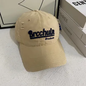 Dettaglio del cappellino da baseball in cotone beige con ricamo 3D blu e effetto usurato