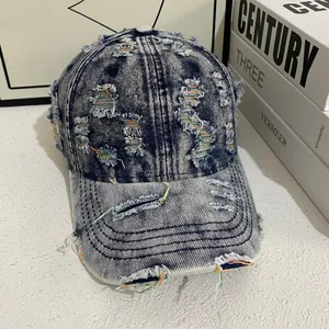 Close-up of distressed denim baseball cap with frayed holes and colorful stitch detail