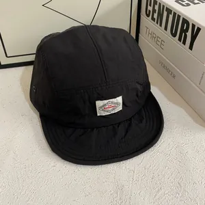 Vista detallada de la gorra camper de nylon negro de 5 paneles con parche de marca tejido