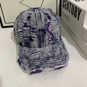 Close-up of distressed denim baseball cap with purple fabric layers and vintage wash detail