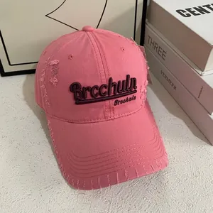 Dettaglio del berretto da baseball rosa consumato con ricamo 3D e bordi vintage strappati