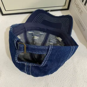 Detailed close-up of distressed denim baseball cap showing bronze buckle and stitching