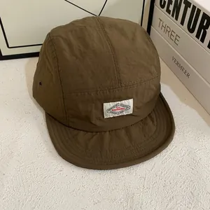 Detalle de gorra camper marrón de secado rápido con etiqueta de tela y ojetes metálicos