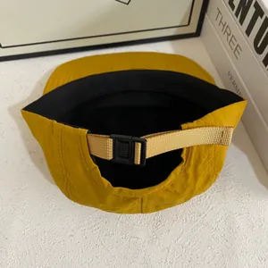 Detalle de gorra de nailon amarillo mostaza con correa negra ajustable y tejido de secado rápido