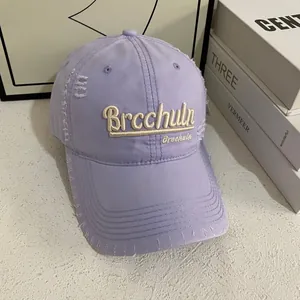 Dettaglio del cappellino da baseball lilla con ricamo 3D e rifiniture effetto consumato