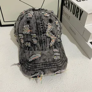 Detail shot of distressed gray denim baseball cap showing torn fabric and colored stitching