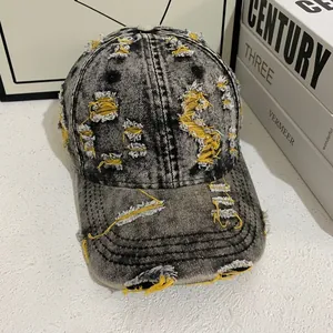 Detailed view of distressed black denim baseball cap with yellow contrast stitching accents