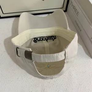 Dettaglio del cappellino crema con fibbia in metallo regolabile e ricamo interno