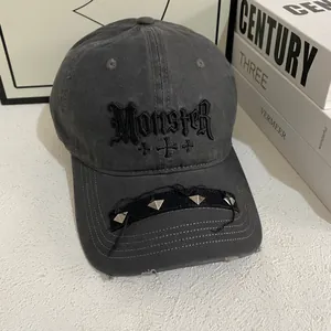 Detail of gothic MONSTER embroidery and silver pyramid studs on distressed grey cotton cap