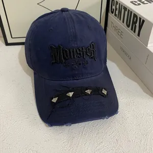Detail of navy baseball cap with gothic Monster embroidery and silver square studs