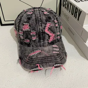 Close-up of distressed vintage denim baseball cap with pink frayed ripped detailing