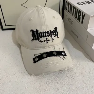 Macro detail of gothic Monster embroidery and metal studs on distressed baseball cap brim