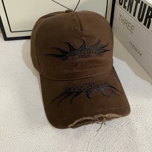Close-up of flame embroidery and distressed frayed edges on brown cotton baseball cap