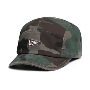 Detail van camouflage camperpet met UDMY-driehoekslogo en metalen ventilatiegaten