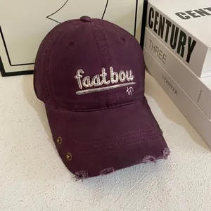 Detailaufnahme der Distressed-Krempe an burgunderroter Cap mit Stickerei und Metallnieten
