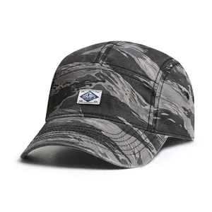 Detailed view of tiger stripe camouflage canvas on a five-panel camper hat with woven label