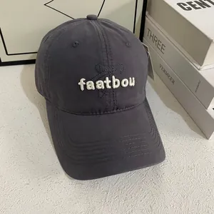 Detail of white 3D embroidery 'faatbou' on a dark grey cotton baseball cap surface